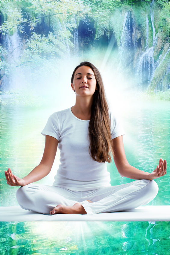 Attractive young woman in white meditating at lake.